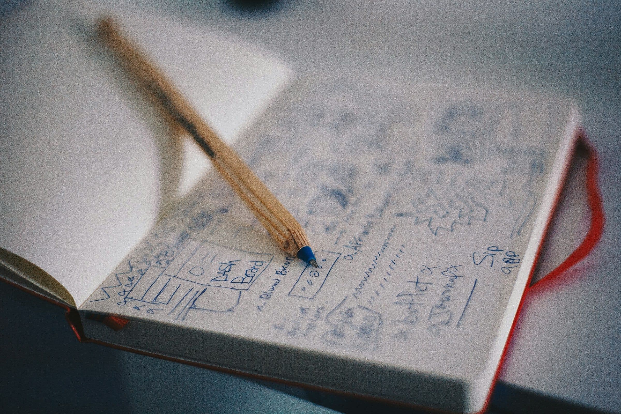 A pencil resting on interface sketches in a notebook