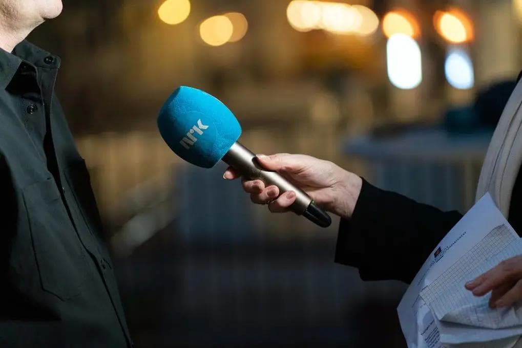 Journalist som intervjuer en person med NRK-mikrofon